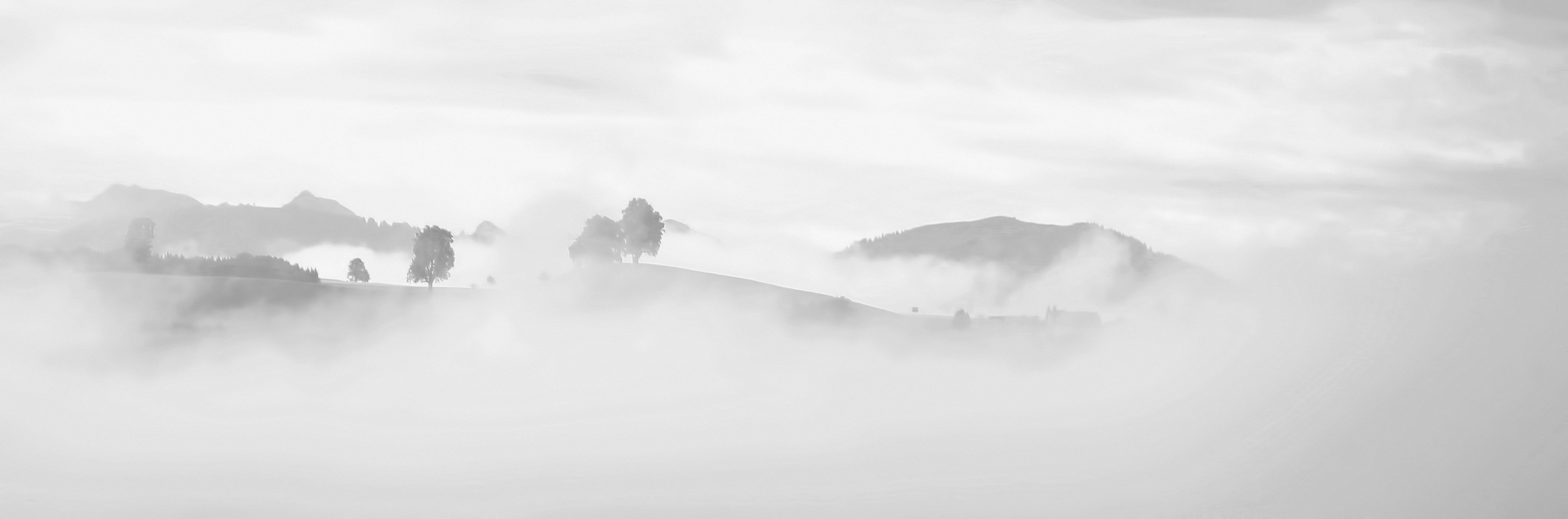 grayscale photography of foggy mountain